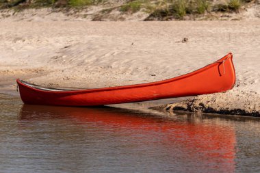 Sakin nehrin kıyısında kumlu bir kano.
