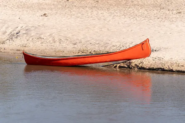 Sakin nehrin kıyısında kumlu bir kano.