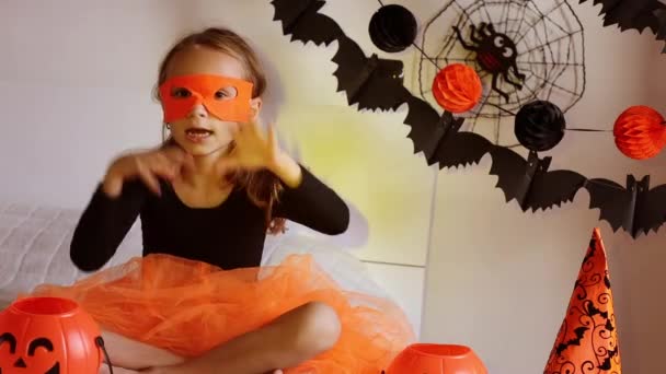 Niña en traje de bruja con cubo de caramelo de calabaza de Halloween en casa, evoca y hacer magia. Fiesta de Halloween. Decoración festiva para el hogar — Vídeo de stock