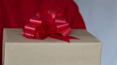Kadınların elinde hediyeler var. Hızlı teslimat. Kırmızı kazaklı genç bir kadın kırmızı fiyonklu bir karton kutu tutuyor. İnternetten alışveriş indirimi. Karantinaya alın. Çevrimiçi dağıtım 