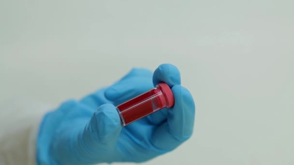 의사들은 검사를 위해 혈액 샘플이 들어 있는 시험관을 손으로 잡는다. 혈액 검사 컨셉. 성혈 - 19 분석을 위한 혈액이 들어 있는 튜브. — 비디오