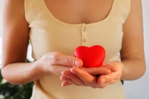 Vrouwenhand houdt het hart vast. Valentijnsdag. Gezond hart, liefde en liefdadigheid, vrijwilligerswerk, moederdag, liefde — Stockfoto