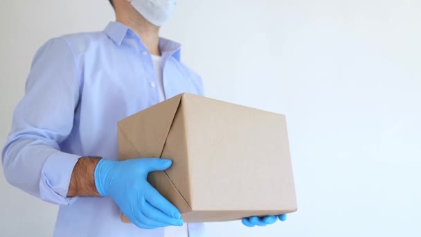 Entrega hombre sosteniendo caja de cartón en máscara médica y guantes médicos. Envío exprés, compras en línea. Caja de donación de Coronavirus. Comida de reparto. Ayuda alimentaria. — Vídeos de Stock