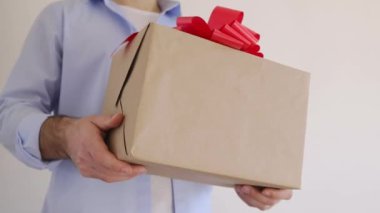 Mans kırmızı kurdeleli bir hediye kutusu tutuyor. Teslimat Ekspresi, Noel indirimi. İnternetten alışveriş. Sevgililer Günü 
