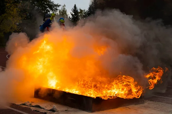 Firefighter extinguishes fire with fire extinguisher during a training competition.