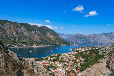 St. John Kalesi 'ne giden tepeden manzaralı panoramik manzara. Kalenin duvarının bir kısmı ön planda görünüyor. Aşağıda kırmızı çatıları ve Kotor Körfezi olan Kotor şehrini görebilirsiniz.