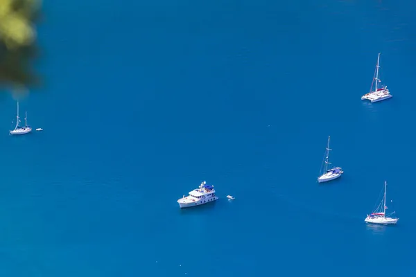Kotor Körfezi 'ndeki yatların nefes kesici panoramik manzarası. Koyun sakin, berrak mavi suları ve kıyıya demirlemiş beyaz zevk yatları.