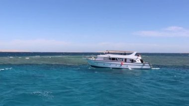 Mavi denizin arka planında beyaz zevkli motorlu tekne, mercan resifi ve bulutlu mavi gökyüzü, Kızıl Deniz 'de yürüyor, açık denizde dalıyor ve şnorkelle yüzüyor, tüplü dalış yapan tekneler