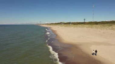 İki kadın kumsalda yürüyor, bir dronun manzarası