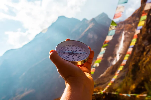 Iránytű a kézben a háttér elmosódott hegy és ima buddhista zászlók. — Stock Fotó
