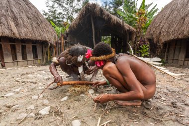 Wamena, Endonezya - 9 Ocak 2010: Geleneksel elbise yakma ateşinde Dani kabilesinin erkekleri. Endonezya Yeni Gine