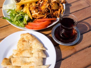 Geleneksel Türk yemeği, patates kızartması, domates, soğan ve salata ve Türk çayı ile birlikte tavuk doner kebabı.