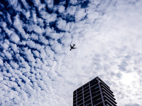Airplane flying in the sky above the skyscraper. Tel-Aviv, Israel