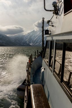 View from the bow of the yacht to the Kamchatka mountains. Sunbeams penetrate the sunset clouds. Concept of summer vacation at sea for travel agencies.