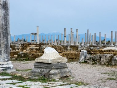 Türkiye 'nin Antalya kenti yakınlarındaki Antik Perge kentindeki dağların arka planındaki mermer sütunlar