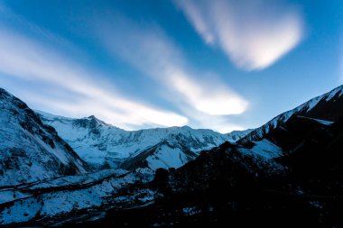 Sisli dağ günbatımı. Akşamları bulutlar dağların üzerinde. Mavi seyahat arkaplanı.