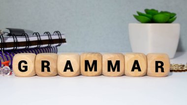 Yanmış harflerle gramer ahşap küpleri, farklı dillerin gramerini öğrenme, gri arka plan üst görünümü, rastgele harflerin etrafına dağılmış küpler.