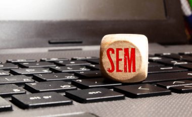 Arama motoru pazarlama. SEM sözcüğü ahşap küplerle ilgili, küpler yansıtıcı yüzeyde duruyor, arka planda bir iş diyagramı var. İş ve finans kavramı