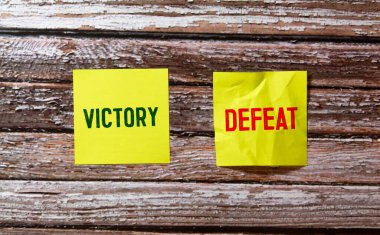 Yenilgi vs Zafer kelimeleri sarı arka plan üzerinde eski kağıt üzerinde yazılı