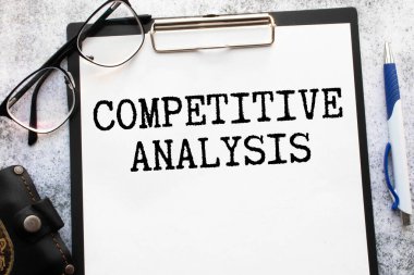 Mavi arkaplanda metin COMPETITOR ANALYSIS ve ofis araçları içeren beyaz not defteri