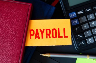 Yazıt bordrolu bir plaka. Finansal bir belgenin not defteri ve hesap makinesi. İş konsepti