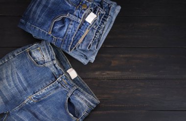 Koyu siyah ahşap bir masada dinlenen mavi kot pantolon. Modern moda kotları - metin kopyalamak için alanı olan üst görünüm.