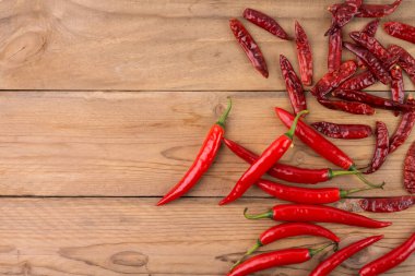 Taze biber ve kurutulmuş kırmızı biber, ahşap zemine yerleştirilmiş, fotokopi alanı ile üst manzara..