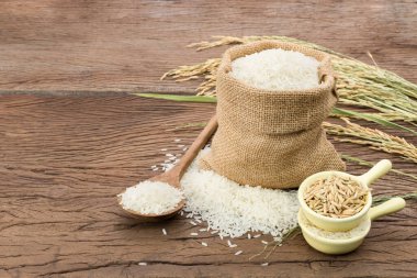 Beyaz organik pirinç ya da pirinç çuvalında yasemin pilavı ve tahta zeminde yatan pirinç kulakları.