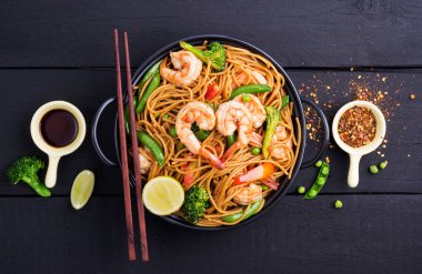 Kızarmış spagetti ya da sebzeli makarna ve siyah kasede karides. koyu arkaplan, üst görünüm