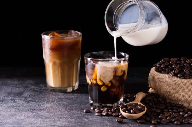 Kahve, sütlü ya da kremalı buzlu latte. Koyu siyah arka plandaki bir kahve dükkanının ahşap masasında.