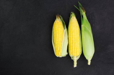 Fotokopi alanı olan siyah ahşap bir masanın üzerinde taze mısır.