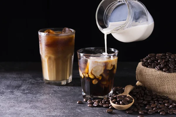 Kahve, sütlü ya da kremalı buzlu latte. Koyu siyah arka plandaki bir kahve dükkanının ahşap masasında.