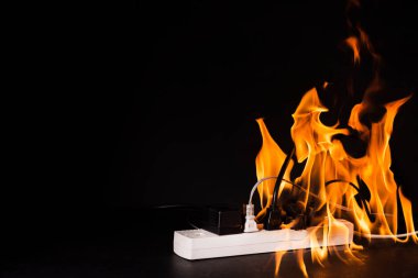 Elektrik kısa devre priz ya da elektronik cihaz alev aldı. Siyah bir arkaplanda standart altı fiş ya da kablo kullanmak