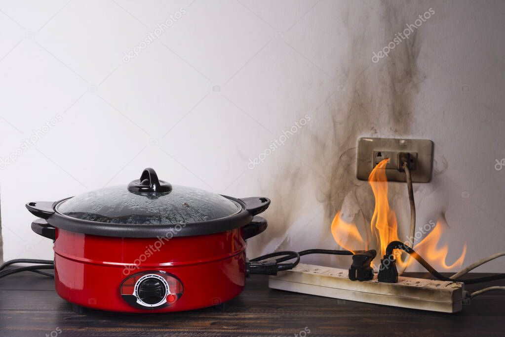 Cooking with an electric pan causes a short circuit. The power plug contains flames and smoke. Fire ignites. Using non-standard equipment is dangerous. overload