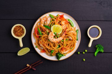 Fried Spaghetti or stir-fried noodles with vegetables and shrimp on a plate. on a dark black background, the top view