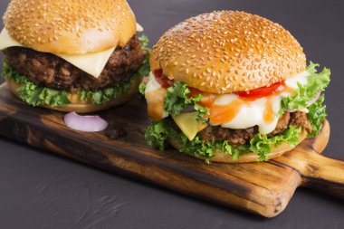 Siyah ahşap bir masada ev yapımı lezzetli hamburgerlerin yakın çekimi. Lezzetli taze pişmiş tavuk, domuz eti ya da sığır burger..