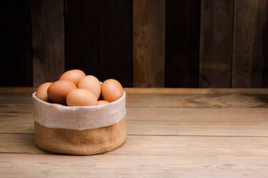 Organik çiftliklerden gelen taze yumurtaları kırsal bir mutfaktaki ahşap bir masada bir çuvala koy. kopyalama alanı ile