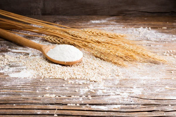 Organic Natural Whole Grain Flour in a Wooden Spoon and wheat seeds Ears of wheat on an old wooden floor