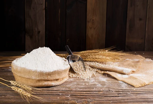 Organic Natural Whole Grain Flour in Sacks and wheat seeds Ears of wheat on an old wooden floor