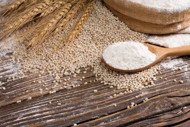 Tahta kaşıkta organik doğal tahıl unu ve buğday tohumu. Eski ahşap zeminde buğday tohumu.