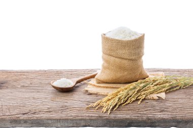 Beyaz organik pirinç ya da çuvaldaki yasemin pilavı ve beyaz arka plandaki ahşap zeminde yatan pirinç kulakları.