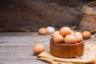 Chicken eggs in a basket placed on a wooden table, rural farm