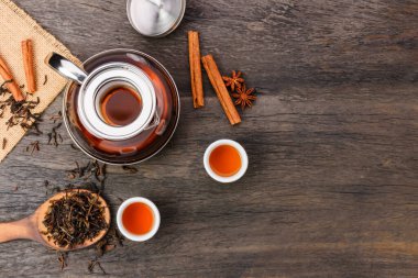 Top view of hot tea in a jug and in a teacup placed on a vintage wood floor.