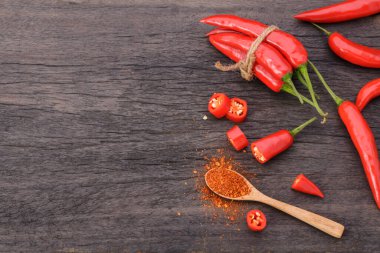Kaşıkta kırmızı biber ve eski bir ahşap masada bir demet kırmızı biber.