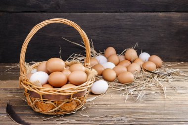 Chicken eggs in a basket placed on a wooden table, rural farm