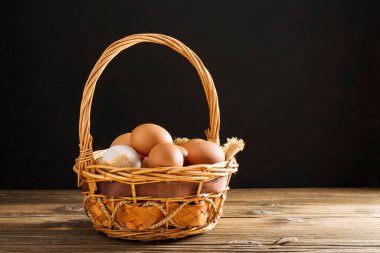 Fresh chicken eggs in a basket on a wooden table with rice straw. Rural farm. High protein food.