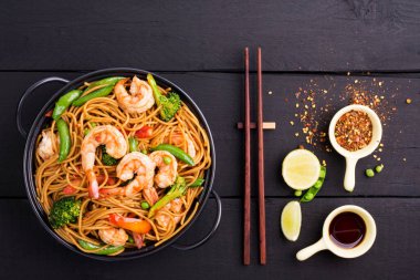 Kızarmış spagetti ya da sebzeli makarna ve siyah kasede karides. koyu arkaplan, üst görünüm