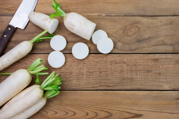 white radish and sliced radishes placed on a simple wooden table with copy space top view