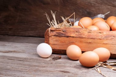Chicken eggs are laid on the ground and put in a basket on a wooden table on, a rural farm