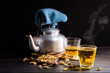 Chrysanthemum tea and Chrysanthemum flowers in a basket on a wood background. Healthy beverage for a drink. Herbs and medical concepts.